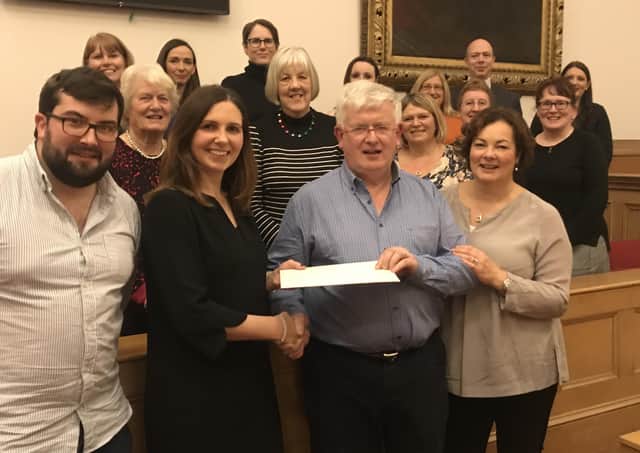 Retiring procurator fiscal Graham Fraser receives a cookery school voucher from assistant procurator fiscal Alison Michie, based at the Crown Office in Edinburgh, watched by his family and procurator fiscal service staff at Jedburgh and Selkirk.