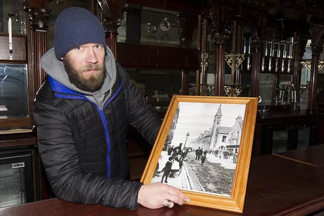 Steve Anderson at the Queen's Head in Hawick High Street with an old picture of the pub circa 1883.
