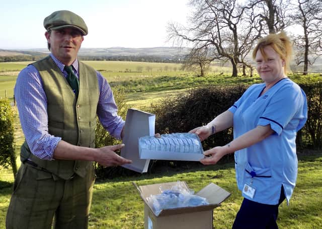 Burncastle Estate head gamekeeper Craig Dickman handing over safety glasses to NHS Borders employee Pam Kennedy.