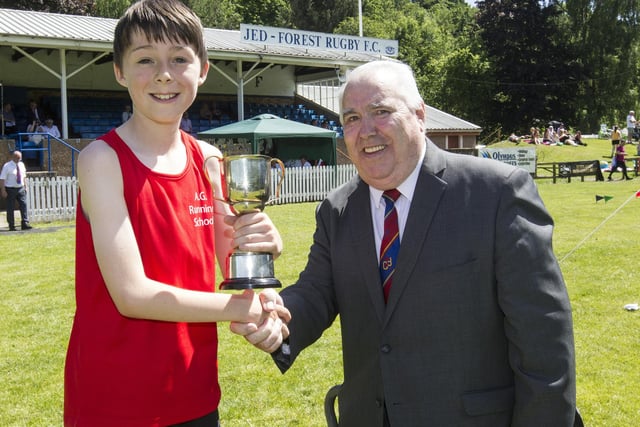 Kelso's Leo Tait being given the 800m youth handicap first prize by Tom McAulay