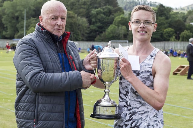 Hawick's Thomas MacAskill being given the John Drysdale Brown Memorial Trophy by Allan Lindsay, of Innerleithen, for winning the 1,600m open handicap