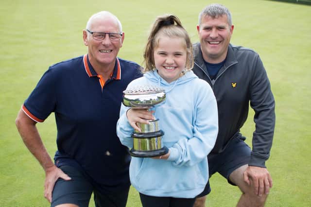Ava Lindores lifts the cup won at Jedburgh Bowling Club by her father, Euan, and grandfather, Robbie, won in the pairs competition (picture by Bill McBurnie)