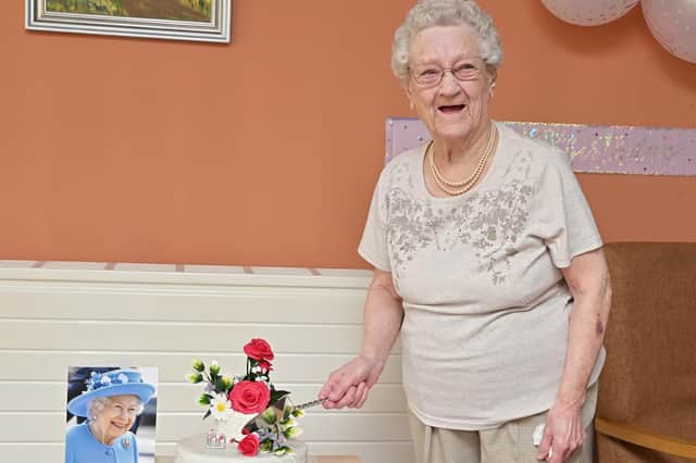 Mary Campbell cuts her 100th birthday cake, with her special message from the Queen.