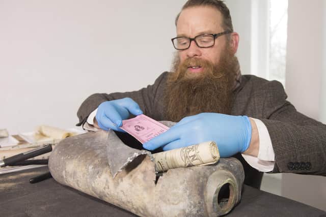 Consultant Conservator Nic Boyes opens the 1898 time capsule discovered during the move of the Burns statue on Constitution Street, Leith, Edinburgh, for the tram works