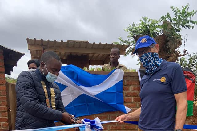 President Daniel Dunga of the Rotary Club of Limbe, Malawi, cuts the ribbon to officially open the new incinerator, alongside Denis Robson.