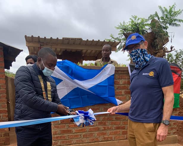 President Daniel Dunga of the Rotary Club of Limbe, Malawi, cuts the ribbon to officially open the new incinerator, alongside Denis Robson.
