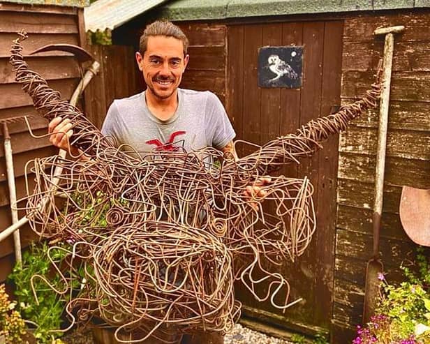 Lee Millar with his highland cow sculpture, made from fencing wire.