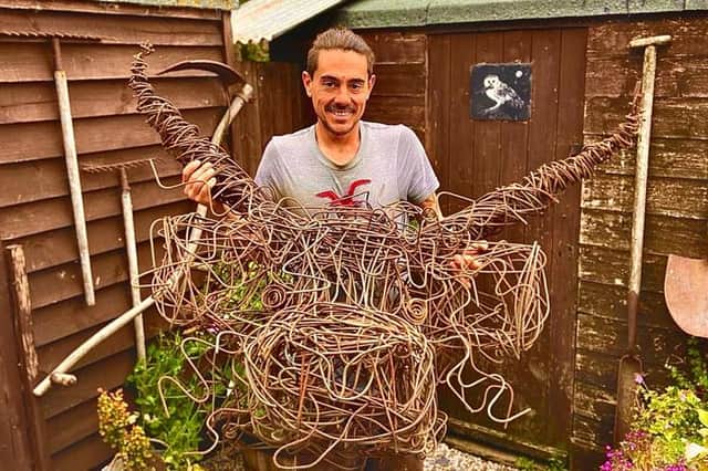 Lee Millar with his highland cow sculpture, made from fencing wire.