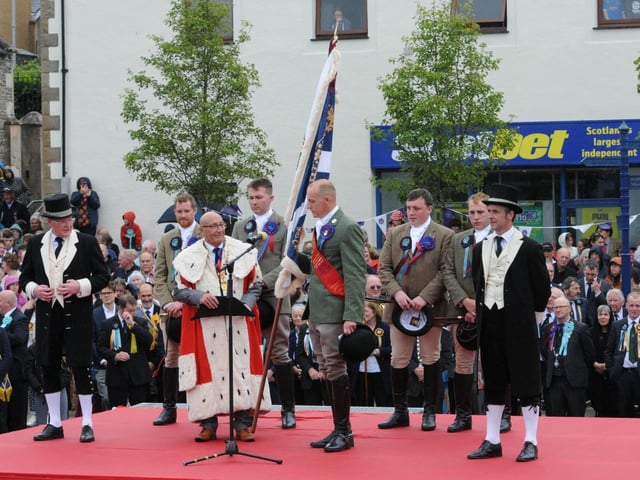 Adam hands the flag back, unsullied and untarnished, to the Provost of the Common Riding, Keith Miller.