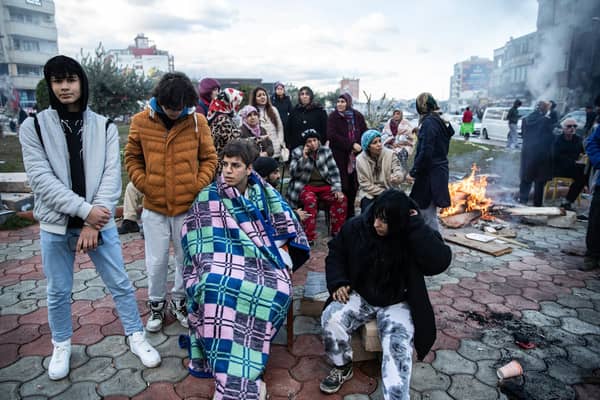 Earthquake survivors sit around a fire in Iskenderun Turkey