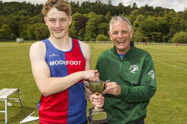 Moorfoot Runner Louis Whyte being handed the youths' 200m handicap trophy by Davie Grieve