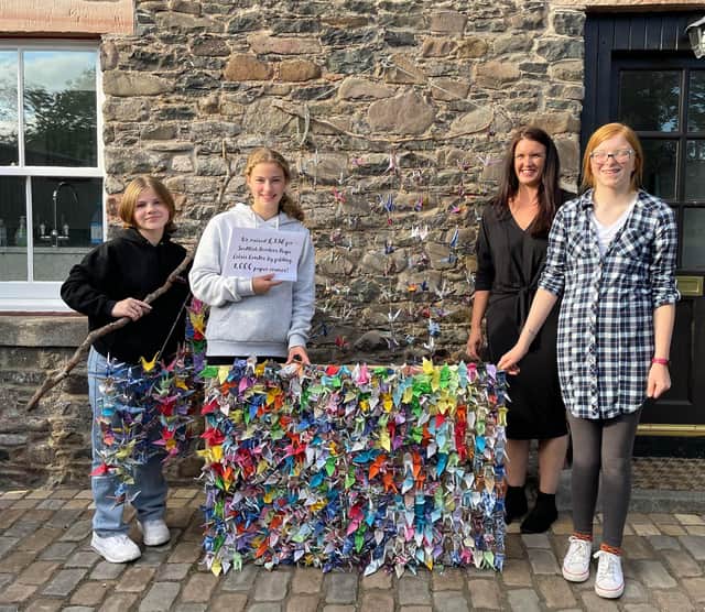 (L-R) Sylvie Armitage, Katy Cameron,  SBRCC director Susie Stein and Annabel Vause stand with some of the 1,000 cranes they folded (stuck to a board in front and hanging from mobiles in the background and in Sylvie's hand)
