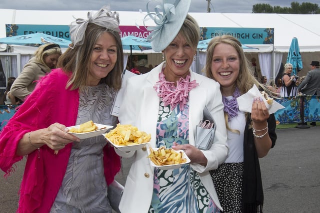 Three spectators getting stuck into some chips at 2022's Kelso Races' ladies' day