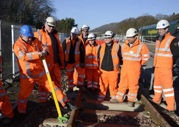 Keith Brown, Cabinet Secretary for Infrastructure. clips the final length of the 30-mile Borders Railway track into place with the installation team.