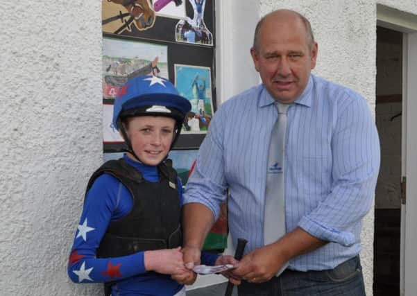 Craig Stanners presents the winner of the second pony race, Robbie Ashe with his prize.