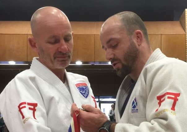 Former Olympian John Buchanan presents Sportif Judo coach Peter Gardiner with the very first medal he won at the Scottish championships