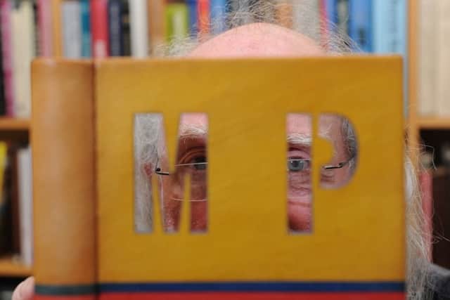 Mark Ramsden peeking through one of the covers of his bound books.