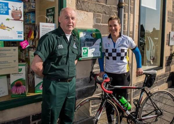 Paramedic Alan Watt from the Scottish Ambulance Service unveils Lauder's defibrillator, which is located outside the pharmacy, with Rosie Cully.