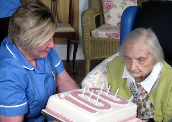 Jenny Pike, with the help of senior carer Lesley Crawford, blows out the candles on her 100th birthday cake during celebrations with other staff members and family at Lennel House Nursing Home in Coldstream.