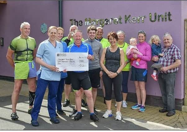 Mark Baxter is pictured with some of his friends and family handing over the cheque to the Margaret Kerr Unit.