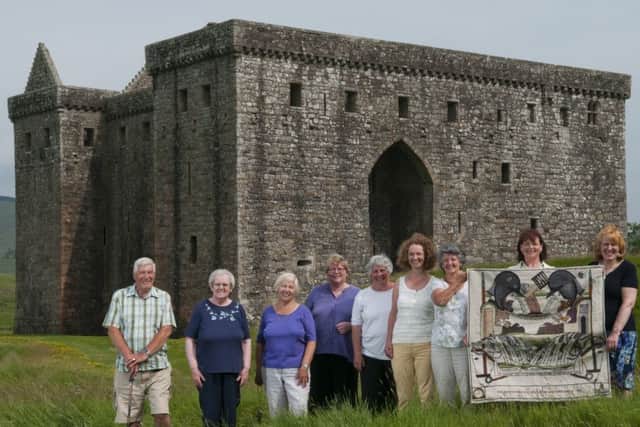 embers of Smailholms stitching group, pictured at Hermitage Castle, with the Great Tapestry of Scotland panel they created.