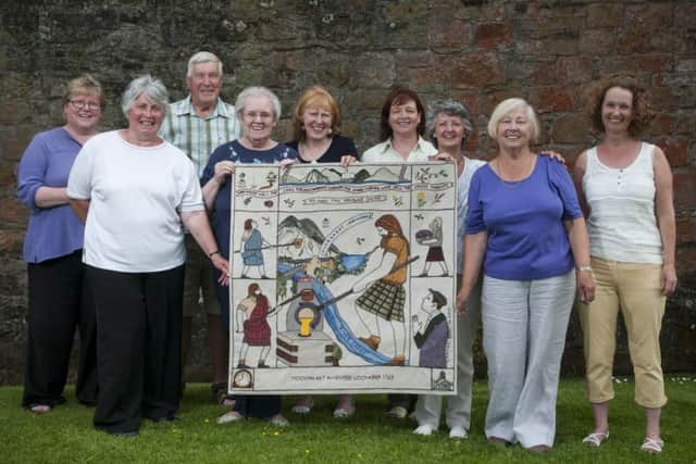 Smailholm's stitching group with one of the 12 tapestry panels created in the Borders.