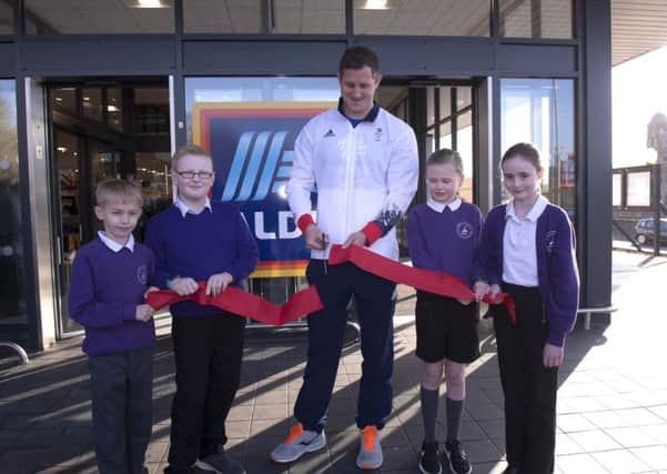 Mark Robertson cuts the ribbon to open the new store, helped by Wilton Primary School pupils.