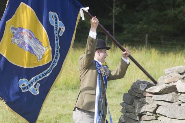 Cornet Chris Rogerson offloads the flag as the cavalcade stops for a rest and sing song at the waterin' stane.