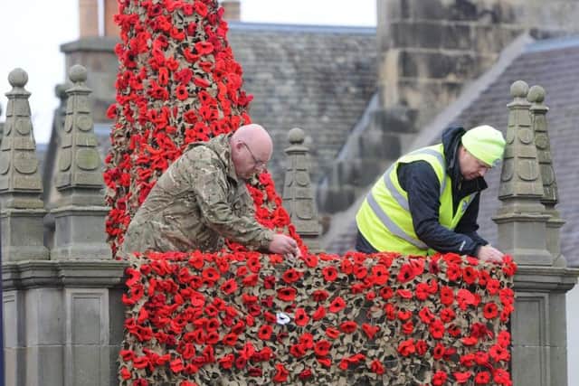 Justin Gilchrist and David Deacon install the poppies on the Pant Well in Selkirks Market Place.