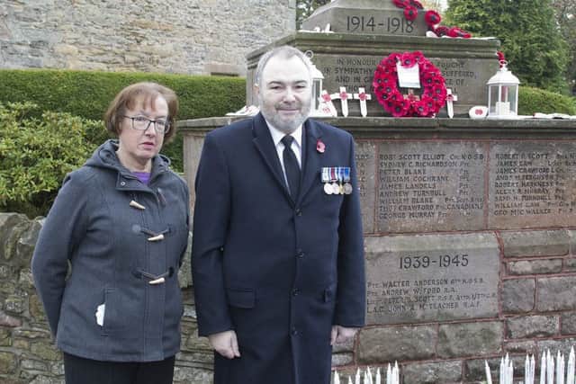 Joyce Crook and Scott Tait admire the candle, poppy and stone tributes on the memorial, after the service.