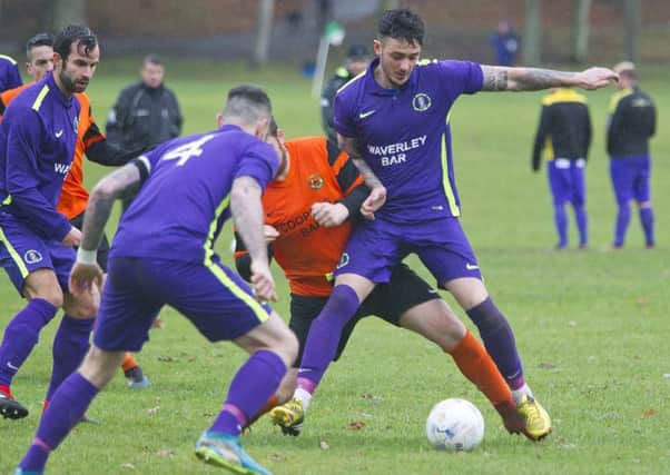 TIght, physical derby action in demanding conditions between Hawick Waverley, in purple, and Hawick United (picture by Bill McBurnie).