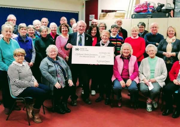 Henry Douglas receives a cheque for £1,000 on behalf of the trustees of the My Name5 Doddie Foundation from Marion Dodd, musical director of the Roxburgh Singers, following their recent performance of Handels Messiah in Melrose Parish Church.
