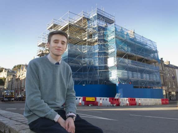 Jedburgh councillor Scott Hamilton in front of the town's scaffolding-clad building in the square.
