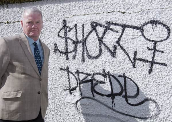 Councillor Davie Paterson investigating grafitti in Hawick.