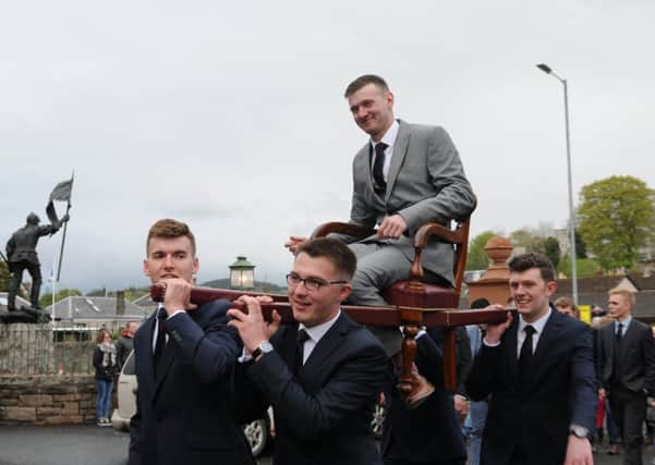 Craig Monks is hoisted into the Victoria Halls on Friday evening by his attendants.