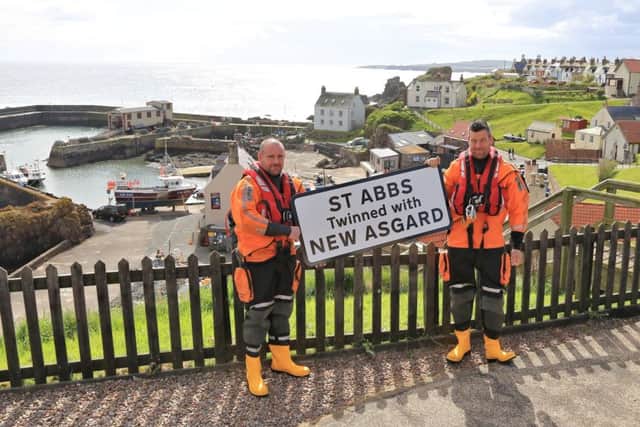 David Wilson, left, and Paul Crowe of the St Abbs lifeboat crew with a sign proclaiming the village to be twinned with the fictional New Asgard.