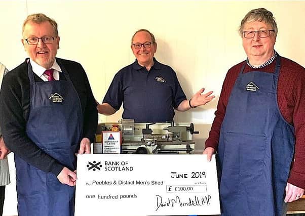 Tweeddale MP David Mundell, second from left, presents a £100 cheque to Peebles and District Mens Shed team members, from left, Tony Butcher, Les Silk, Iain Coates and Malcolm Bruce. The cash will go towards upgrading the groups rented premises, based in the towns Community Hub in School Brae.