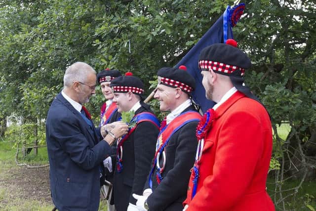 Acting President of the Callant's club Jimmy Steele pins a sprig of from the Capon Tree to Callant Munro's sash.
