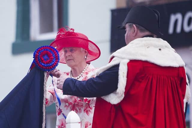 Provost Oliver's wife Helen busses the flag.