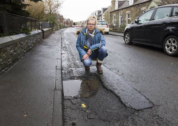 Olga Olesheva investigating potholes in Young Street in Peebles.