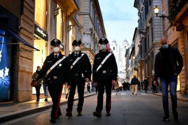 Police officers walk across the Via dei Condotti luxury shopping street in downtown Rome on 13 March, before the government tightened restrictions across most of the country from 15 March (Photo: ALBERTO PIZZOLI/AFP via Getty Images)